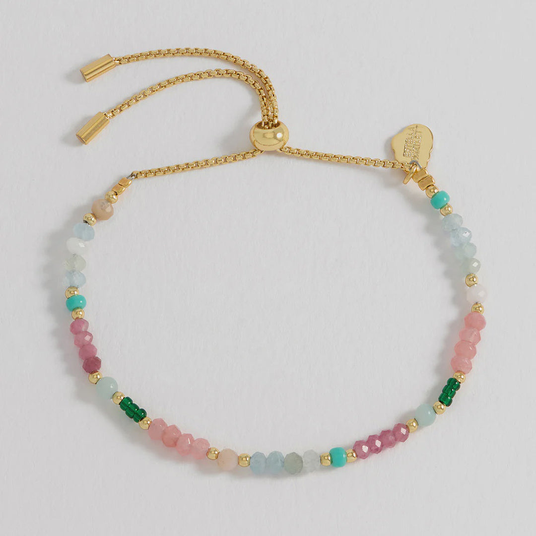 Multicolored beaded bracelet with gold clasp on a light gray background