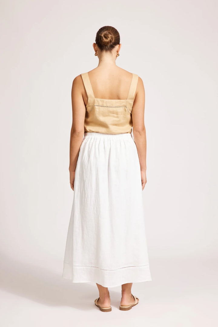 Woman wearing a beige top and white Eb & Ive skirt on a plain background