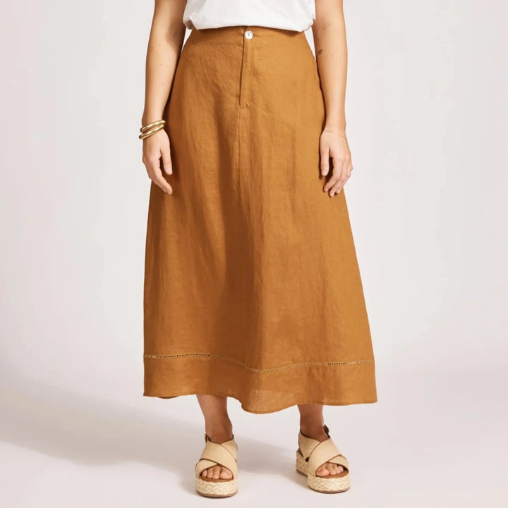 Woman wearing a white top and Eb & Ive brown skirt on a light pink background