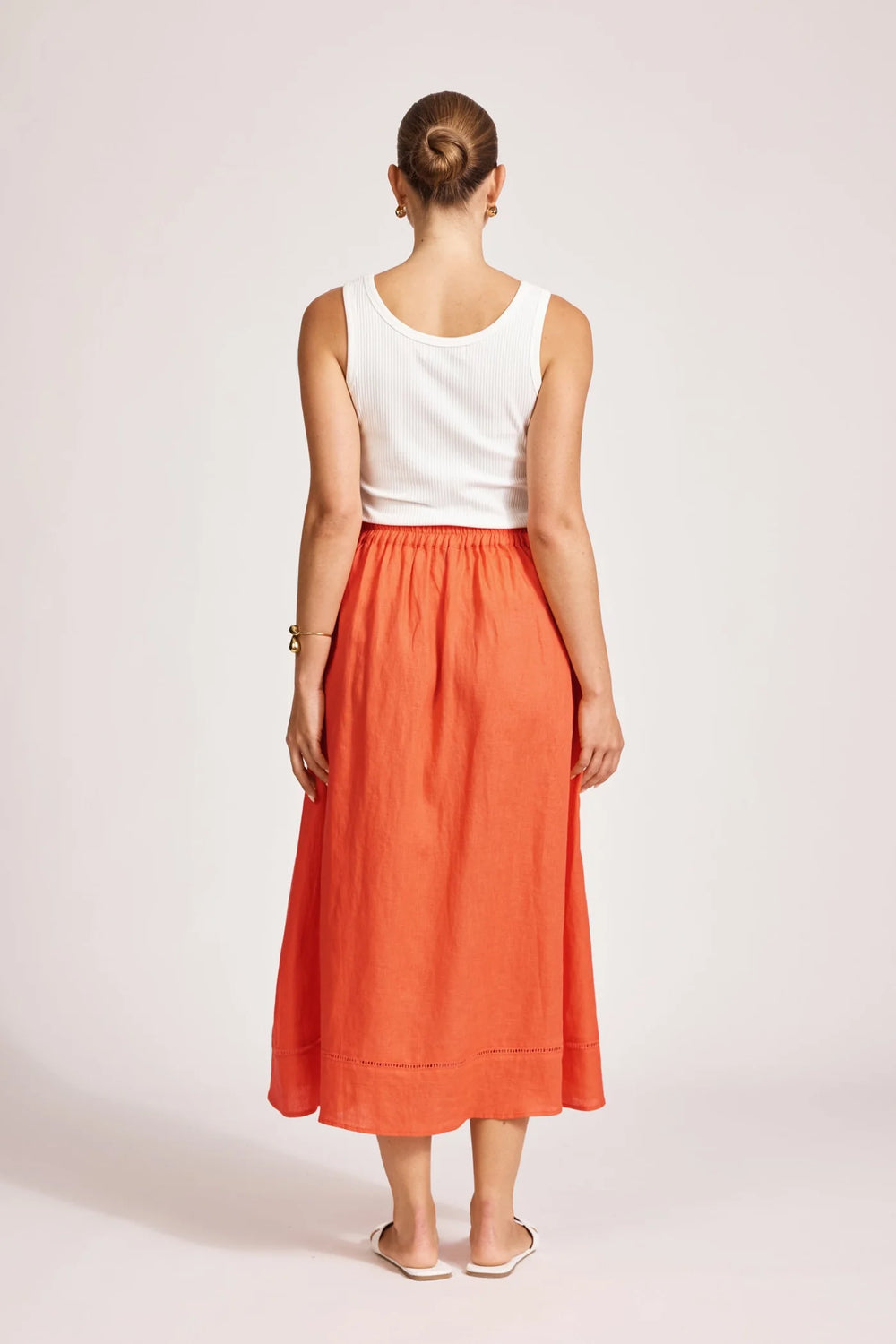 Person wearing a white top and Eb & Ive orange skirt on a plain background