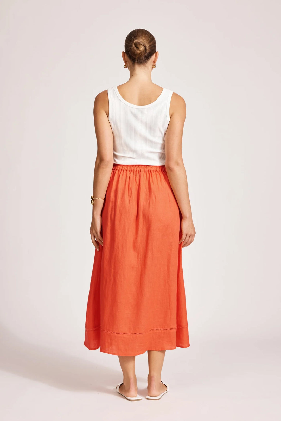 Person wearing a white top and Eb & Ive orange skirt on a plain background