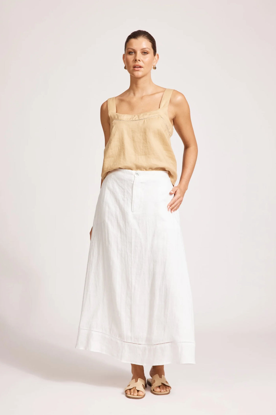 Woman wearing a beige top and Eb & ive white skirt on a white background
