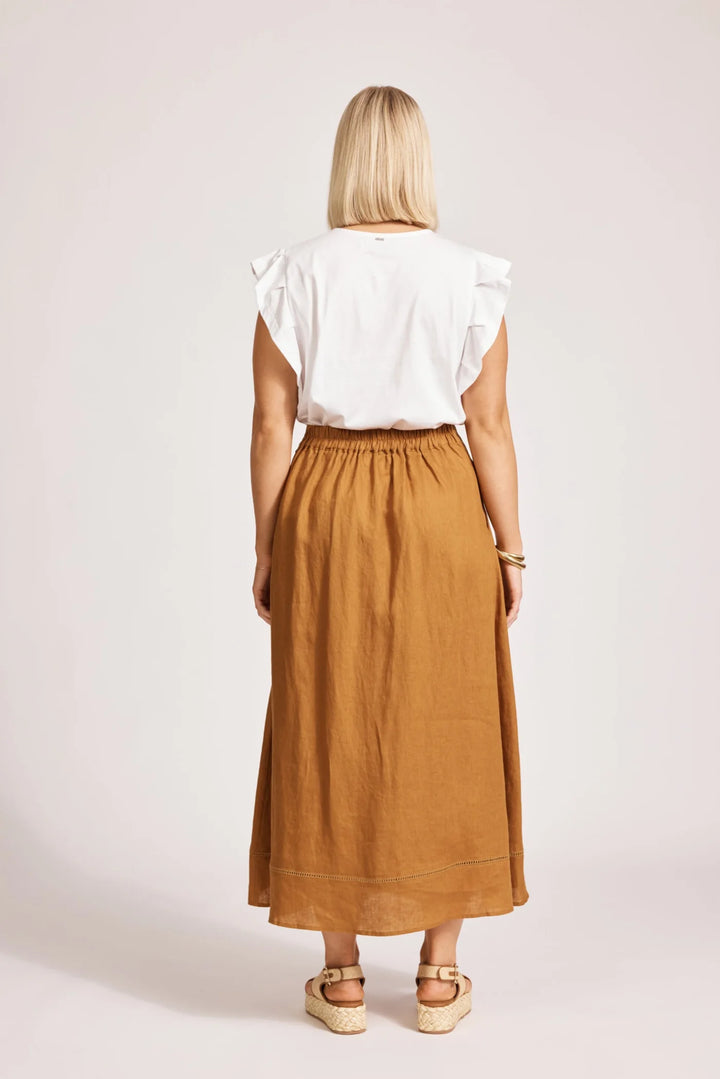 Woman wearing a white top and Eb & Ive brown skirt on a plain background