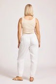 Woman wearing a beige tank top and eb & ive white pants on a plain background