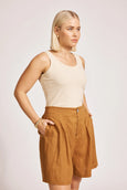 Woman wearing a beige tank top and Eb & Ive brown shorts on a plain background