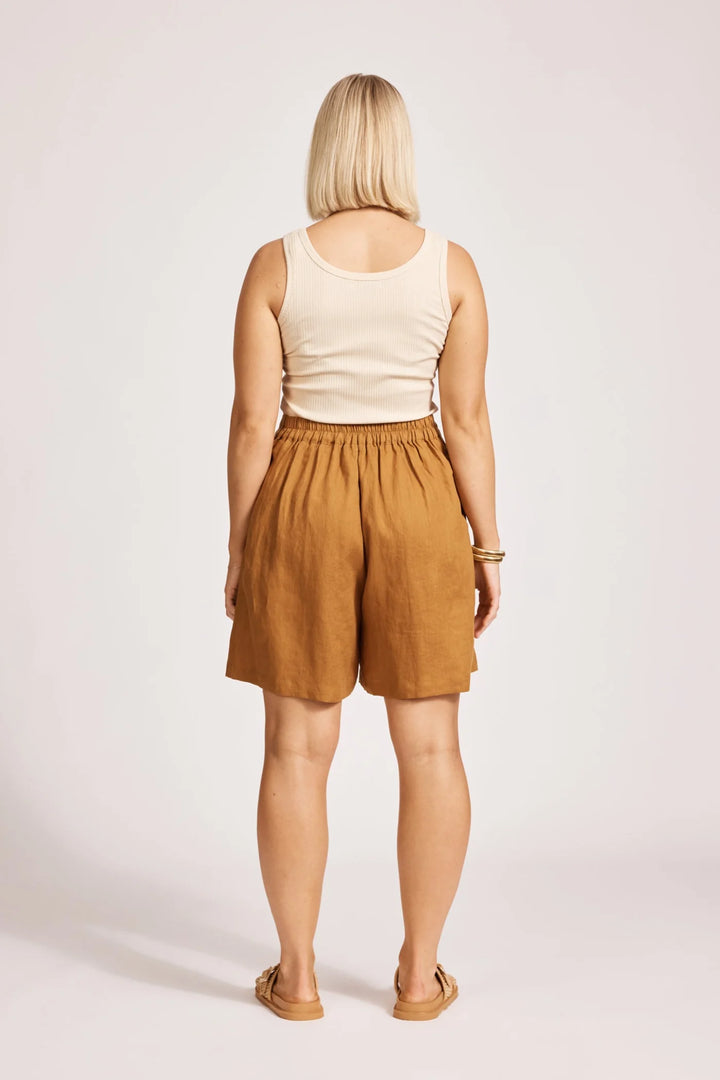Person wearing a beige tank top and Eb & Ive brown shorts on a white background