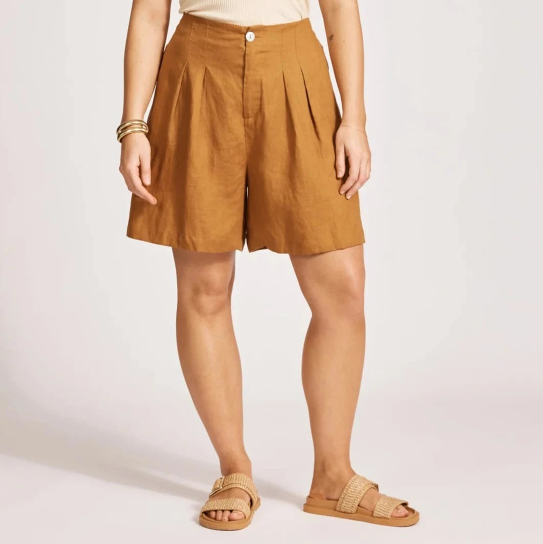 Woman wearing a beige tank top and tan Eb & Ive shorts on a white background