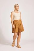 Woman wearing a beige tank top and brown Eb & Ive shorts on a white background