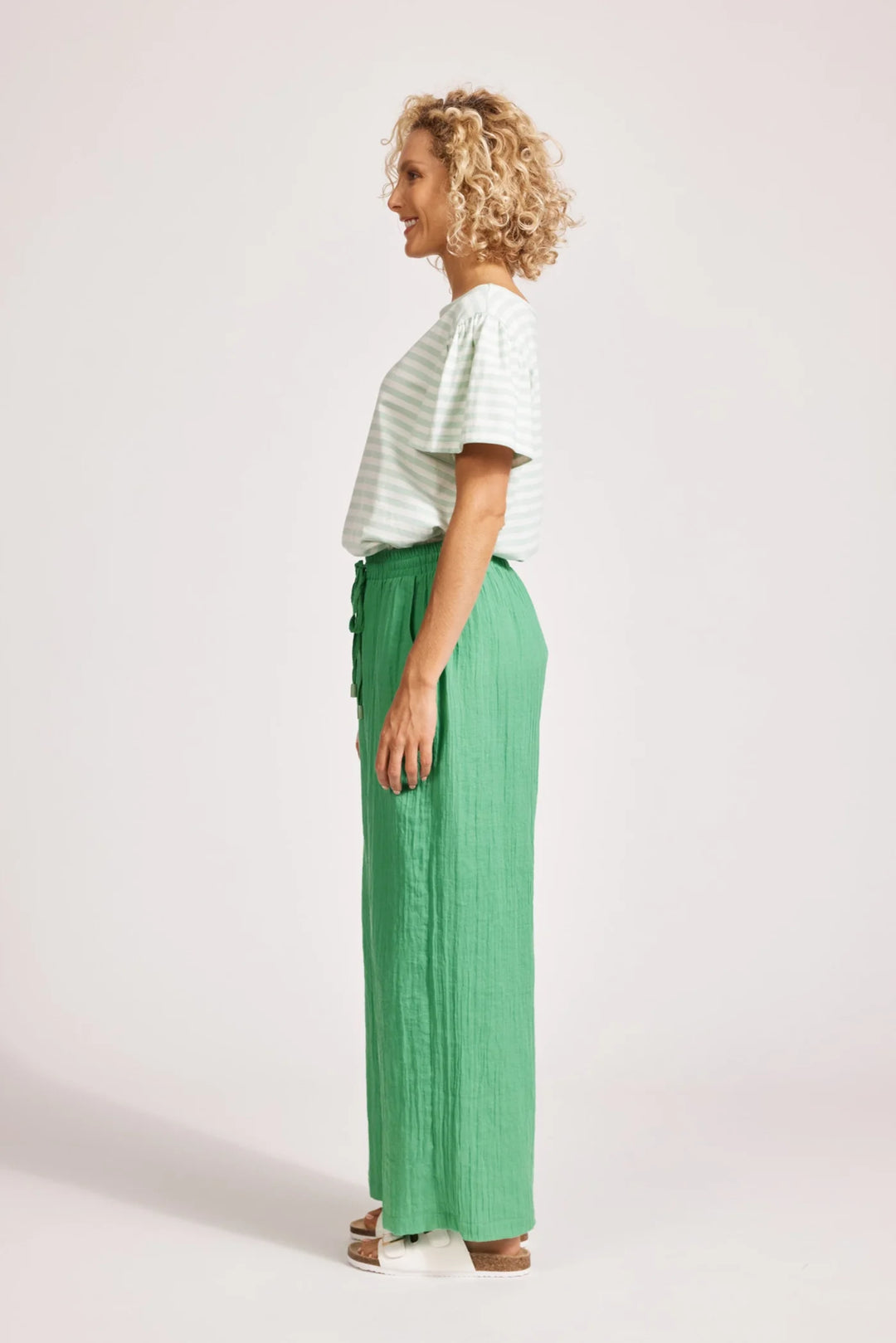 Woman wearing a striped shirt and Eb & Ive green pants on a white background