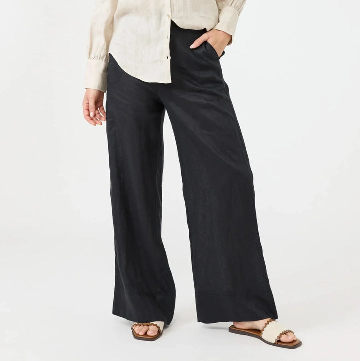 Woman wearing a beige shirt and black Eb & Ive pants on a white background