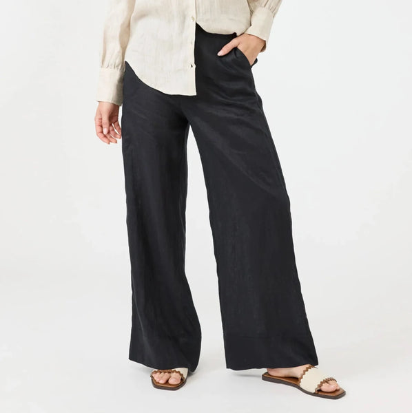 Woman wearing a beige shirt and black Eb & Ive pants on a white background