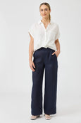 Woman wearing a white blouse and navy Eb & Ive pants on a white background