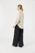 Woman wearing a beige sweater and Eb & ive black pants on a white background