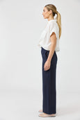 Woman wearing a white blouse and Eb & ive navy pants on a white background