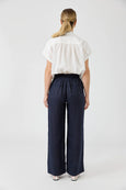 Person wearing a white blouse and Eb & Iv navy wide-leg pants on a white background