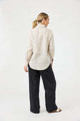 Woman wearing a beige shirt and black Eb & Ive pants on a white background
