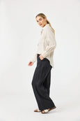 Woman wearing a white blouse and black Eb & Ive pants on a white background