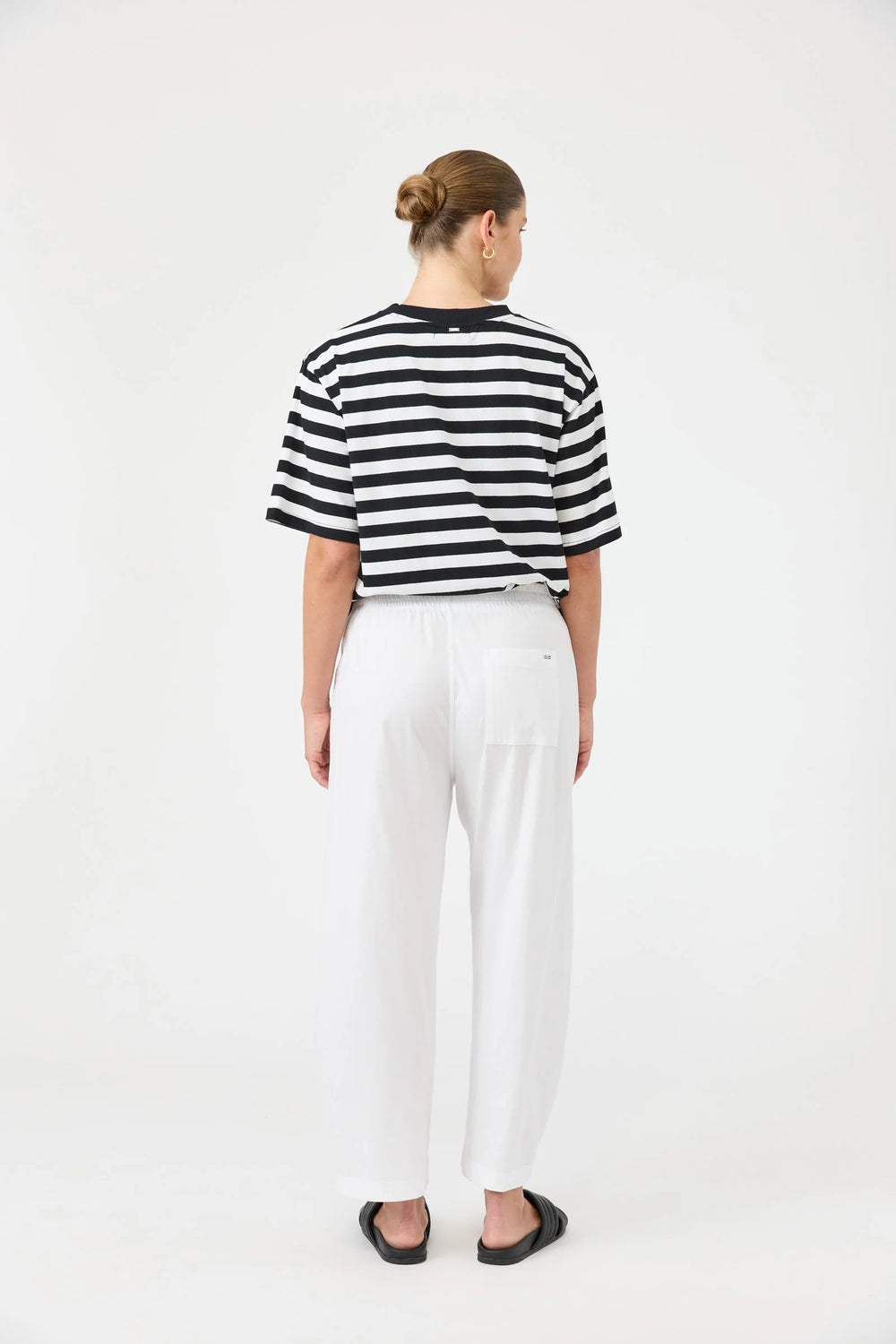 Person wearing a black and white striped shirt and Eb & Ive white pants on a white background