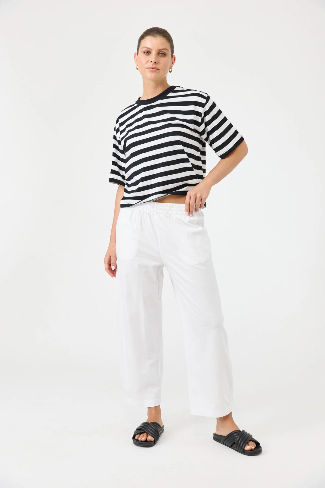 Person wearing a black and white striped shirt with Eb & Ive white pants on a white background