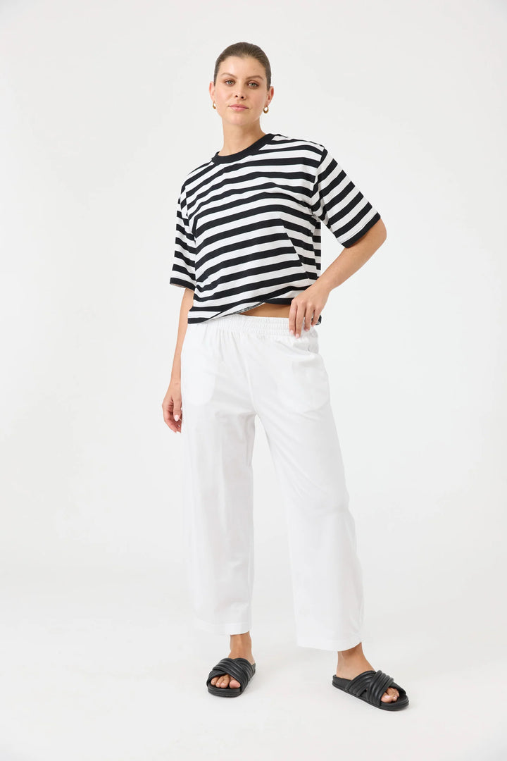 Person wearing a black and white striped shirt with Eb & Ive white pants on a white background