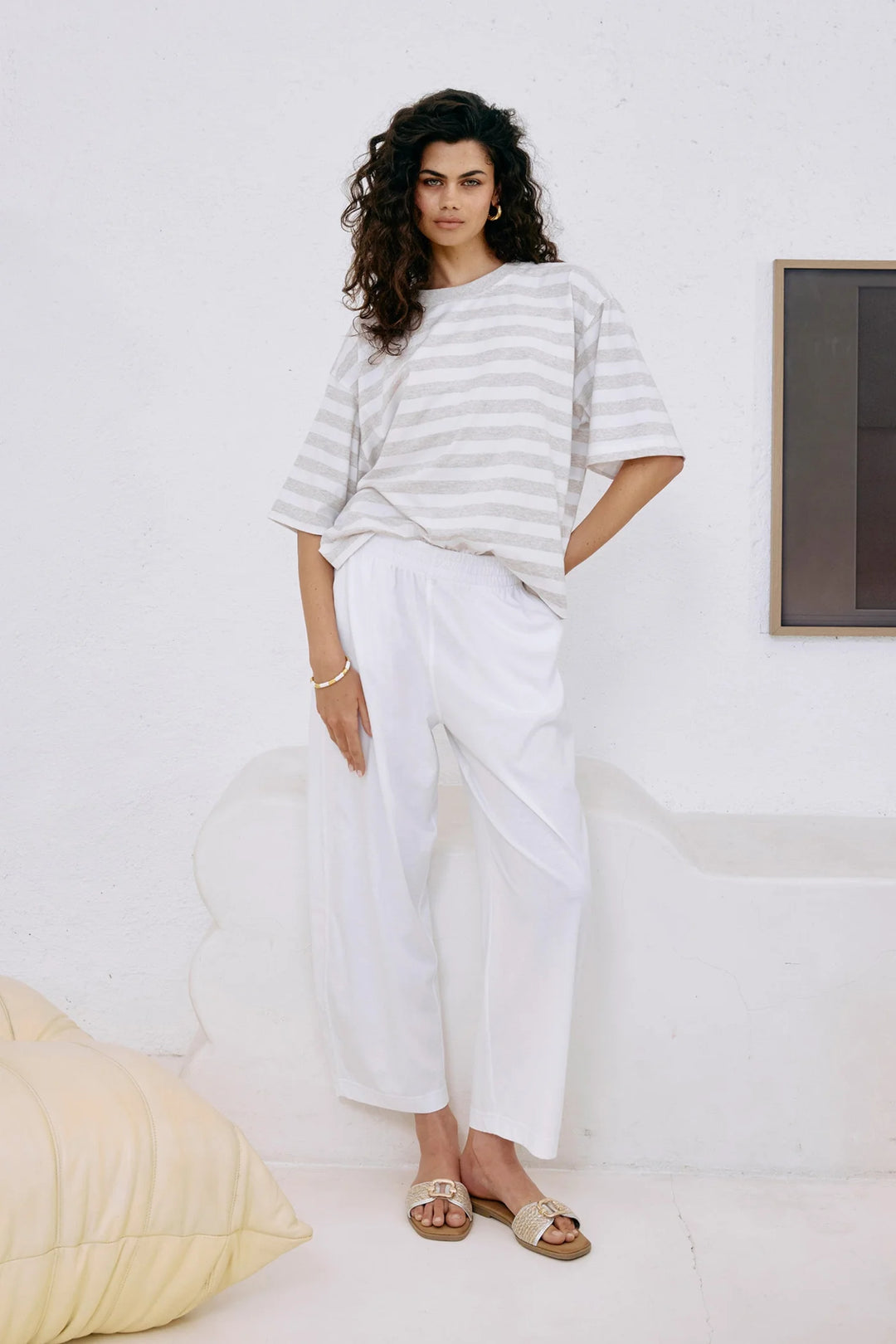 Woman wearing a striped shirt and white Eb & Ive pants in a minimalistic room.