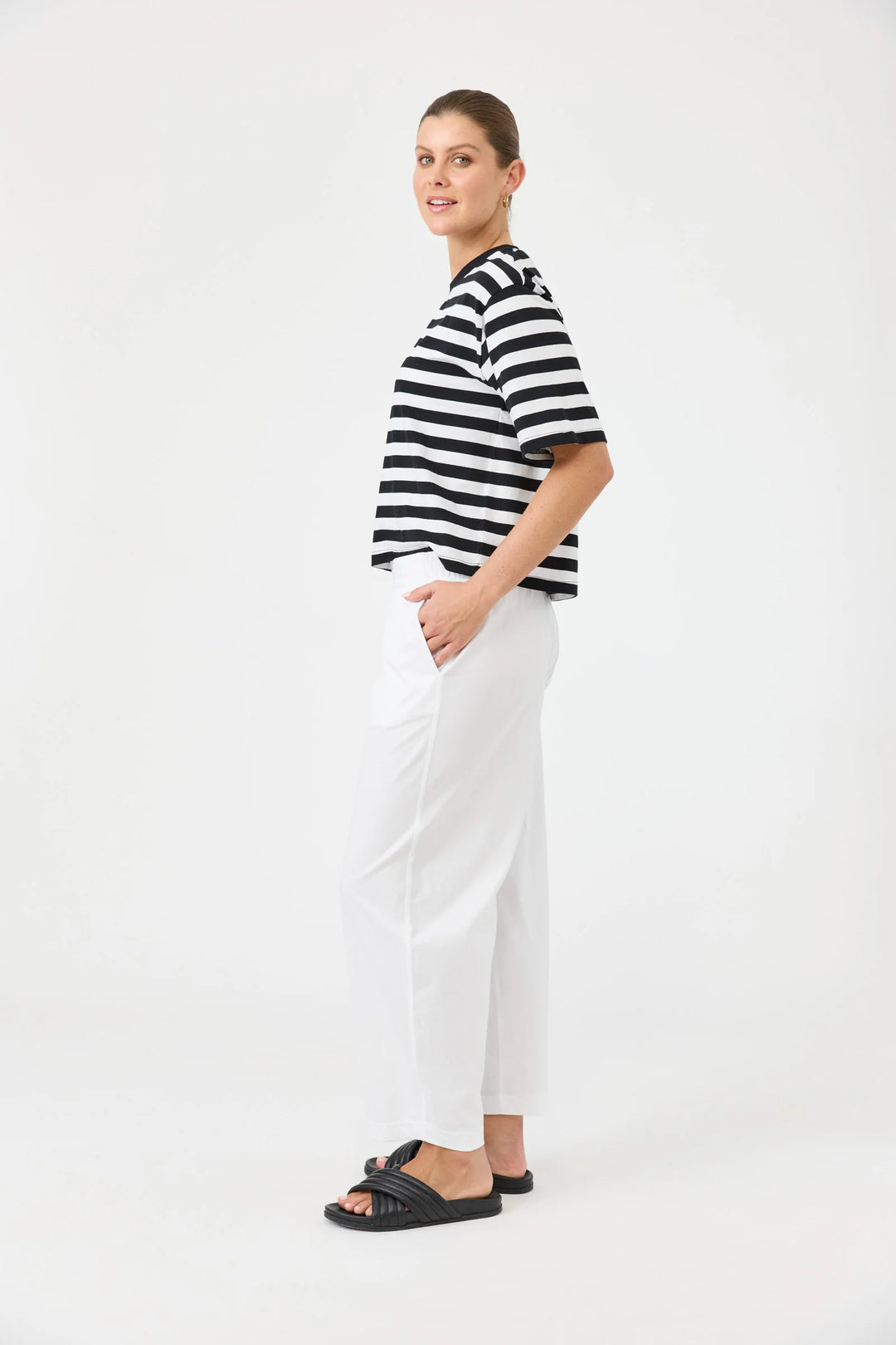 Woman wearing a black and white striped shirt and Eb & Ive white pants on a white background
