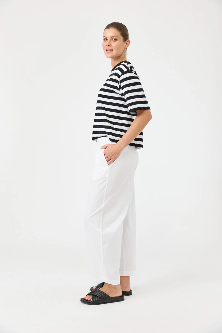 Woman wearing a black and white striped shirt and Eb & Ive white pants on a white background