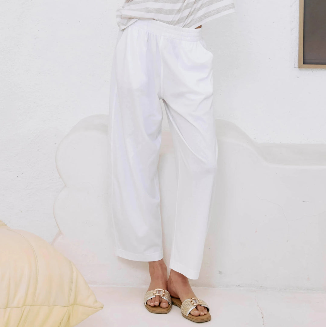 Woman in a white outfit posing against a plain background