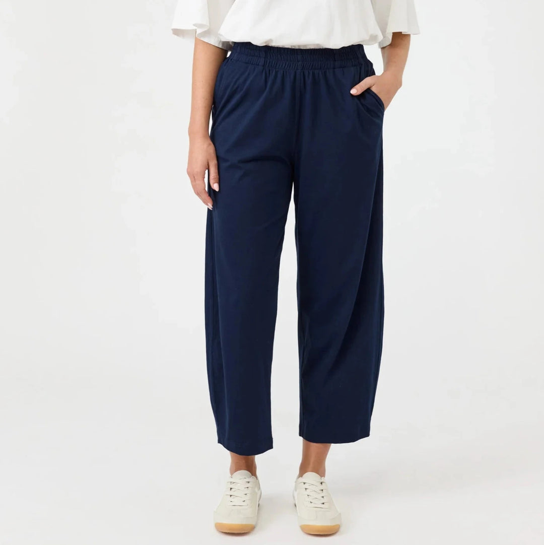 Person wearing a white top and Eb & ive navy pants on a white background
