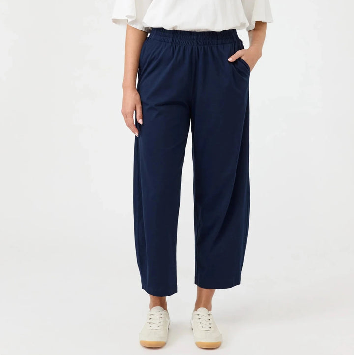 Person wearing a white top and Eb & ive navy pants on a white background