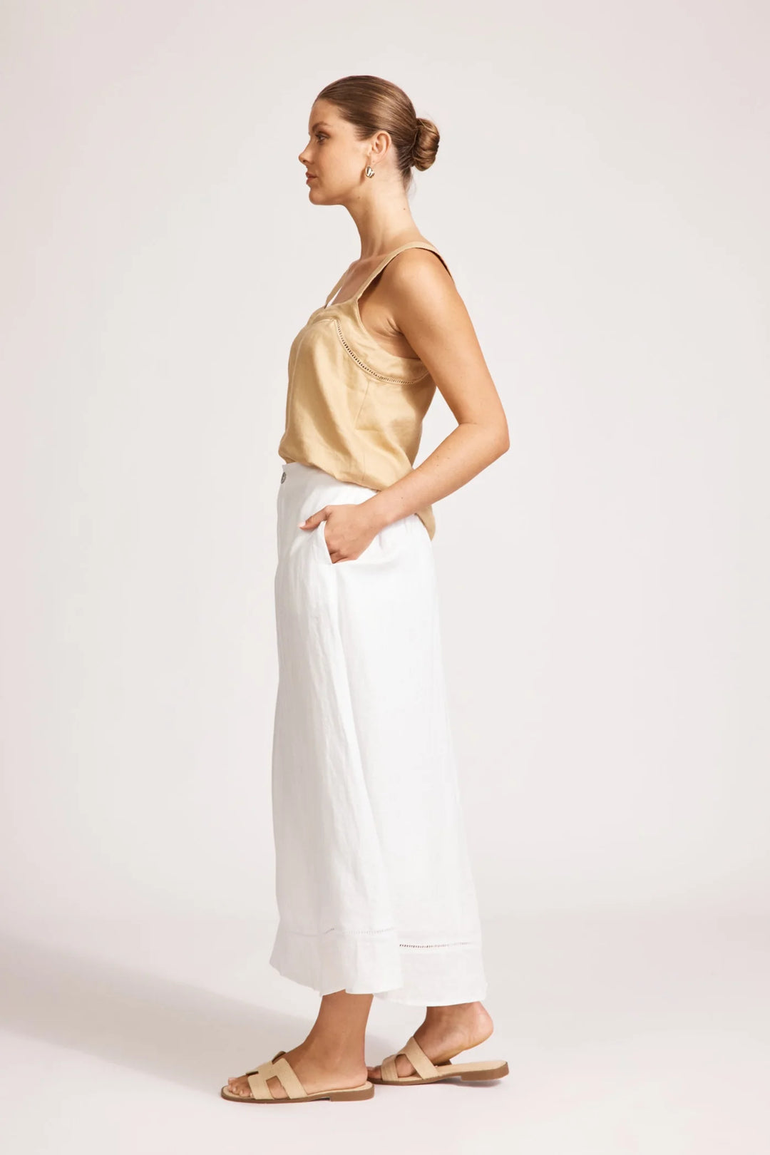 Woman wearing a yellow top and white Eb & Ive skirts on a plain background