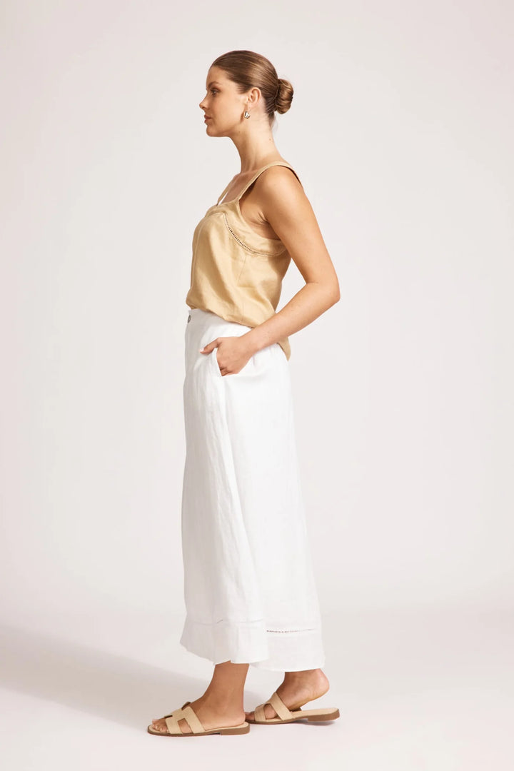 Woman wearing a yellow top and white Eb & Ive skirts on a plain background