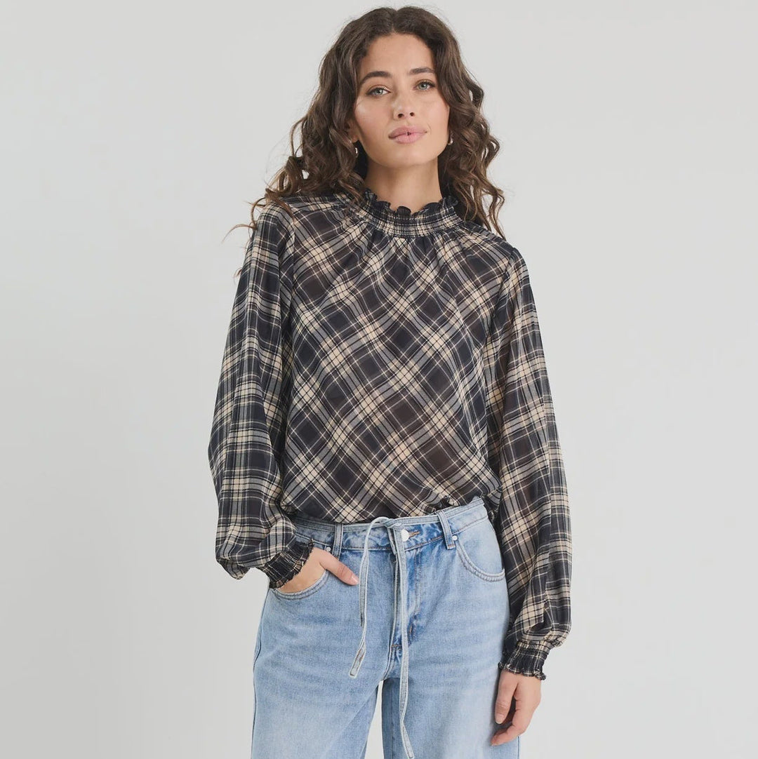 Woman wearing a plaid shirt and light blue jeans on a white background