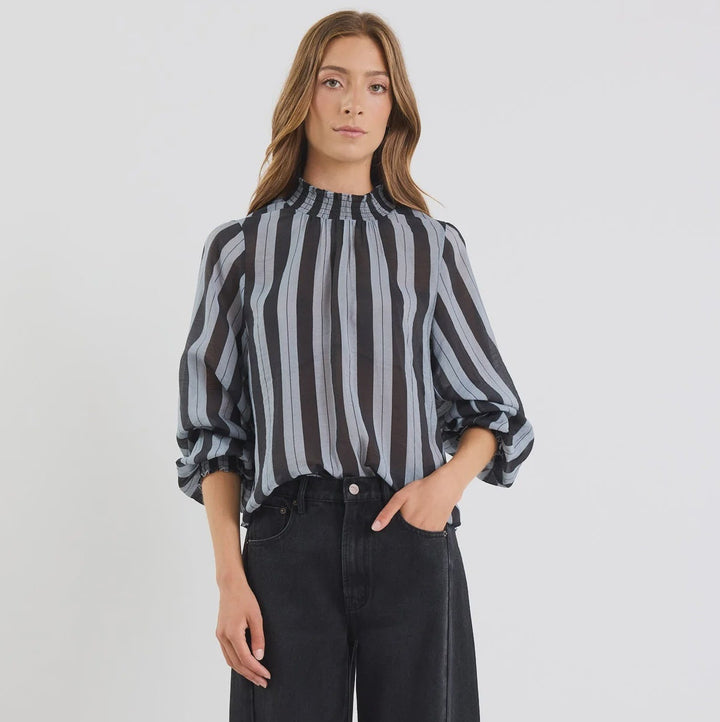 Woman wearing a black and white striped shirt and black pants on a white background
