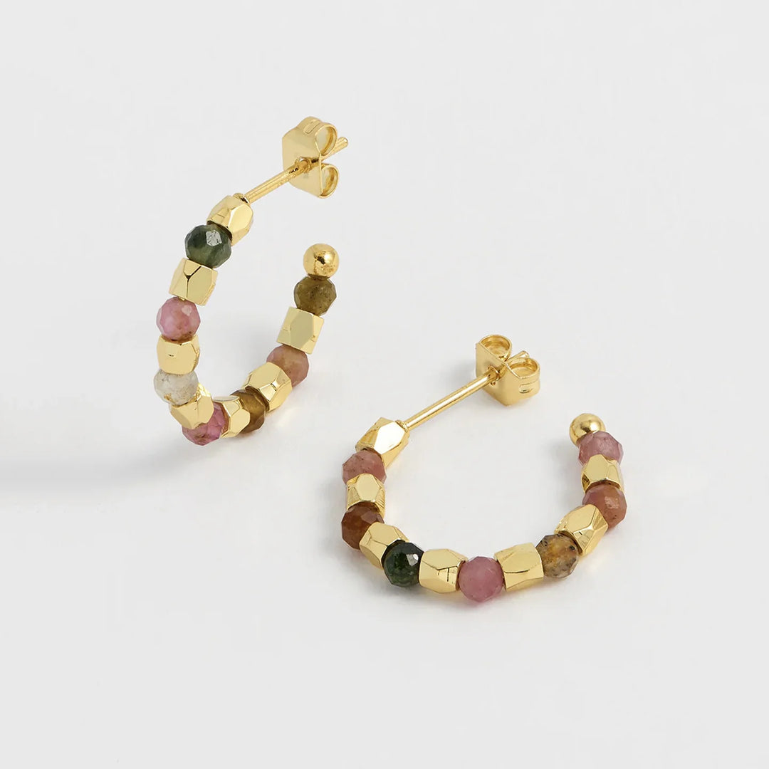 Gold hoop earrings with multicolored beads on a light gray background