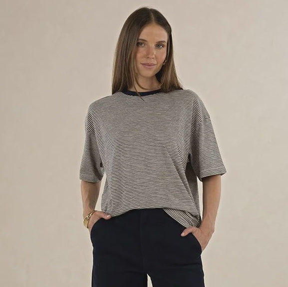 Woman wearing a gray top and black wide-leg pants on a beige background