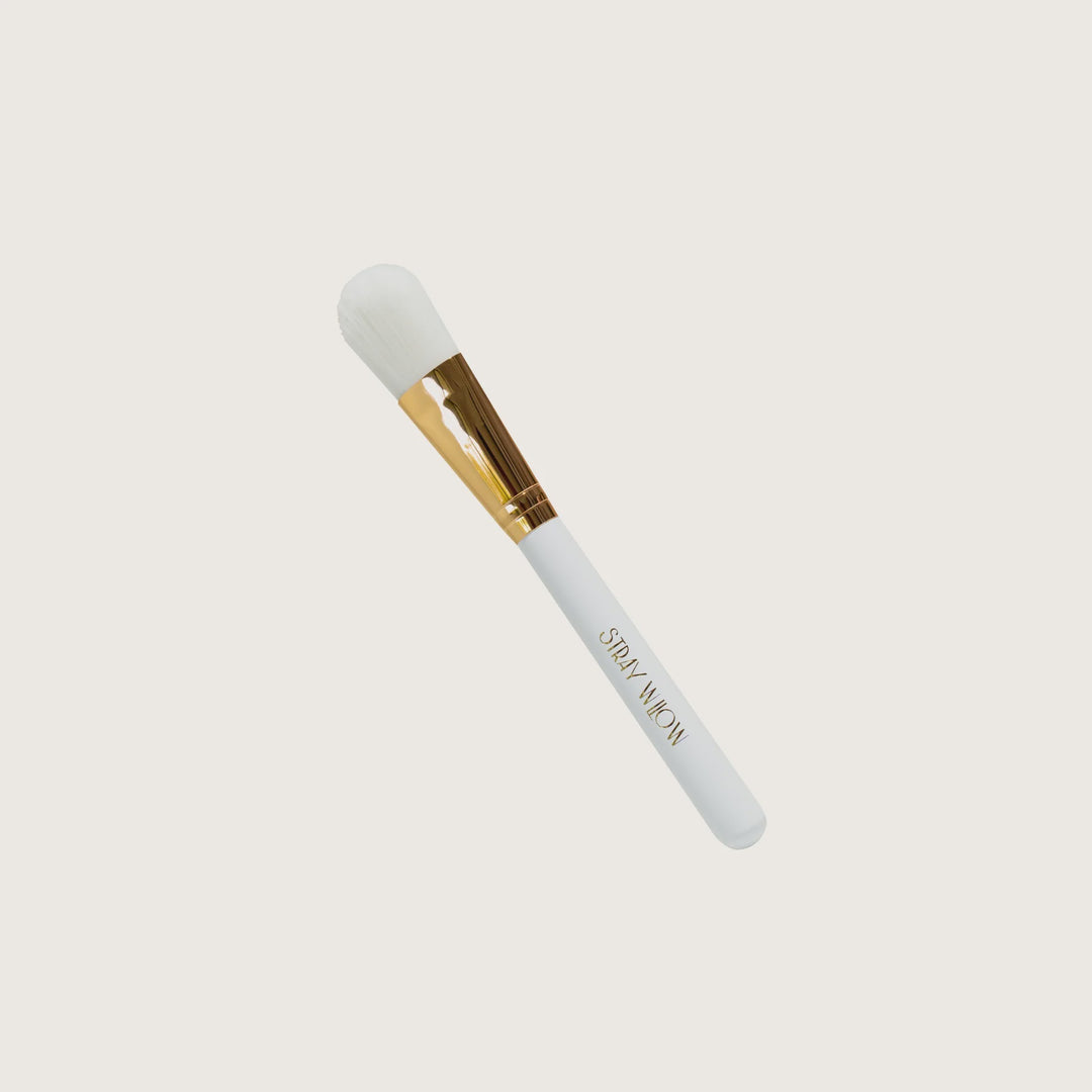 Makeup brush with white ferrule and gold accents on a white background