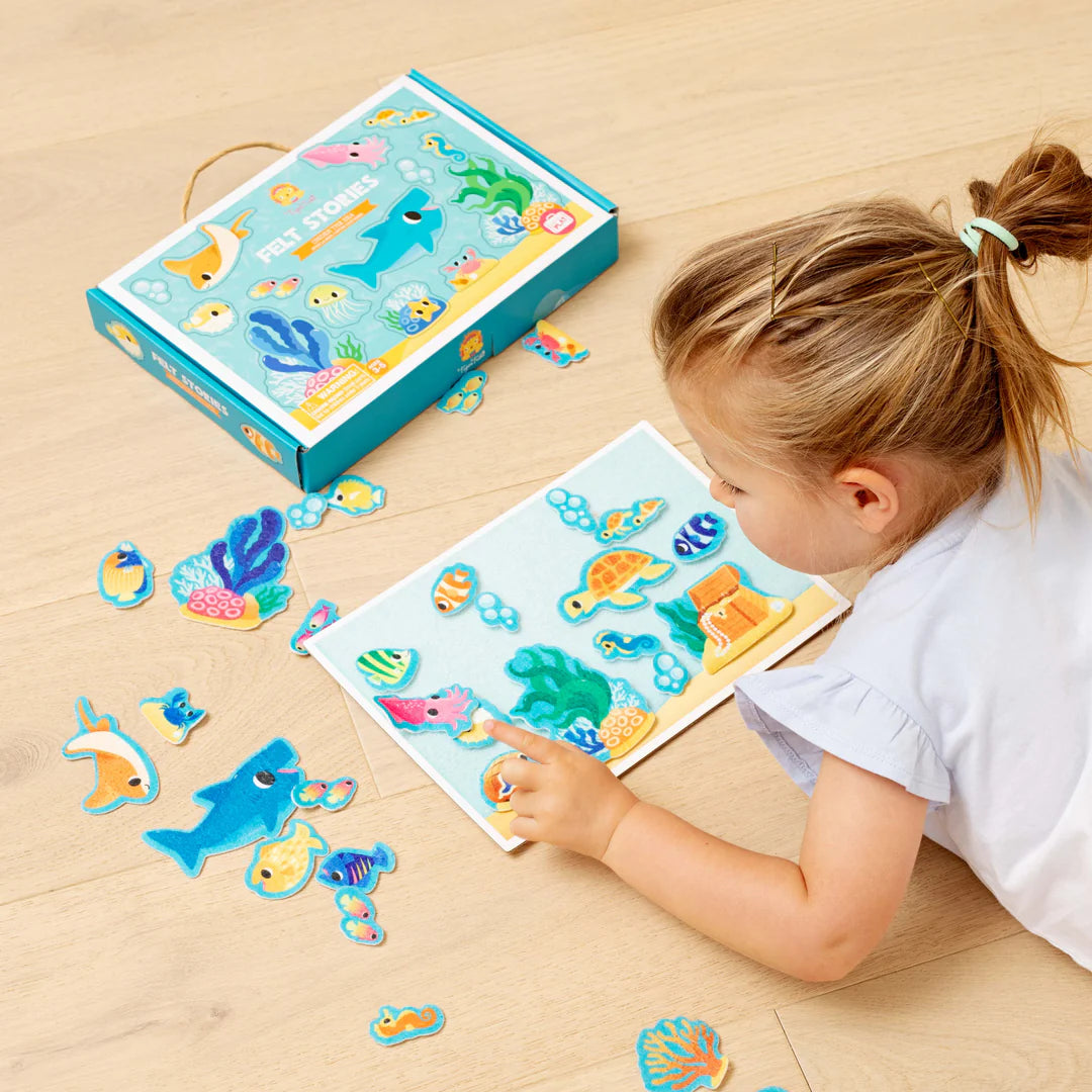 Child playing with an underwater-themed puzzle on a wooden floor