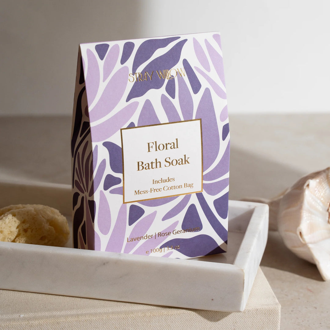 Floral bath soak packaging with purple leaf pattern on a neutral background