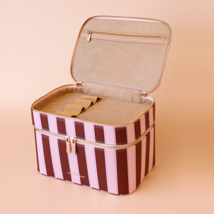 Fox & Fallow Striped makeup case with gold accents on a beige background