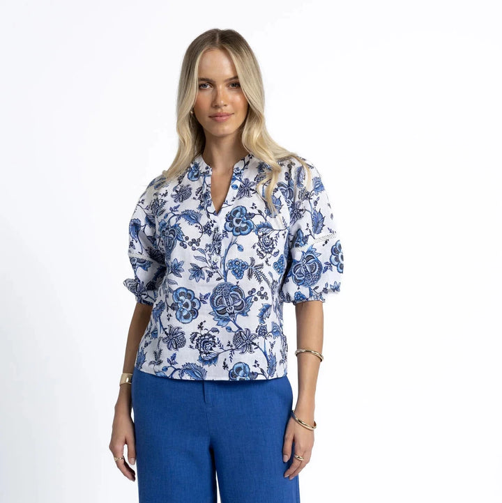 Woman wearing a blue floral blouse and blue pants on a white background