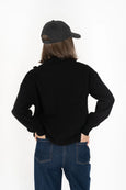 Person wearing a black jacket and cap from behind on a white background
