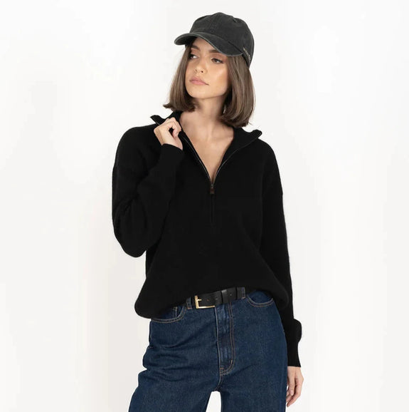 Person wearing a black sweater, blue jeans, and blue sneakers on a white background