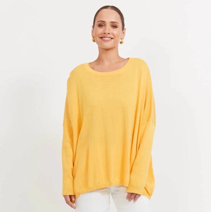 Woman wearing a yellow haven top and white pants on a white background