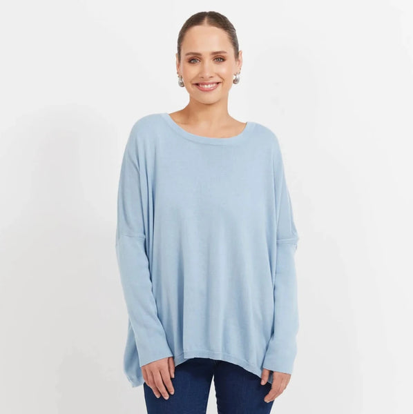 Woman wearing a light blue haven sweater and dark blue jeans on a white background