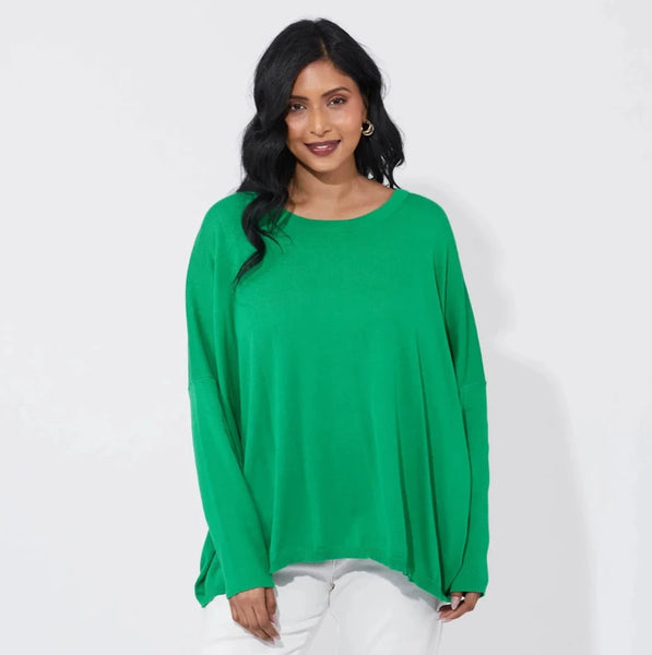 Woman wearing a green haven  top and white pants on a white background