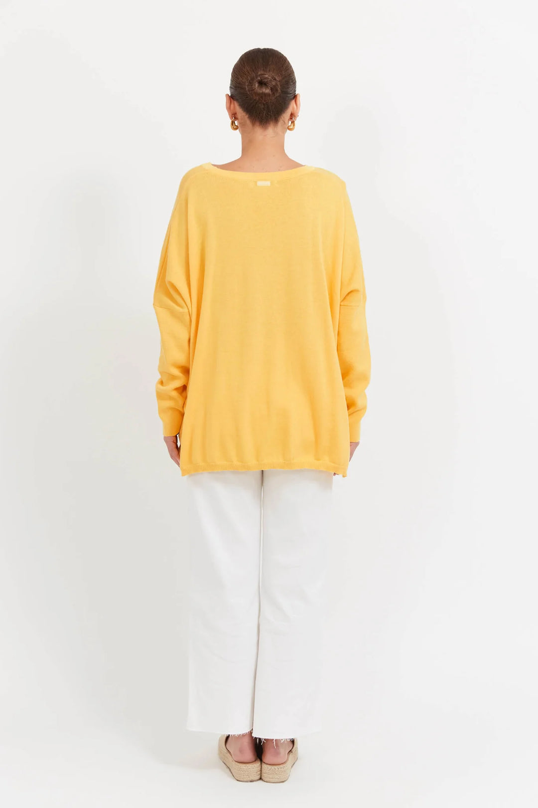 Person wearing a yellow haven sweater and white pants on a white background
