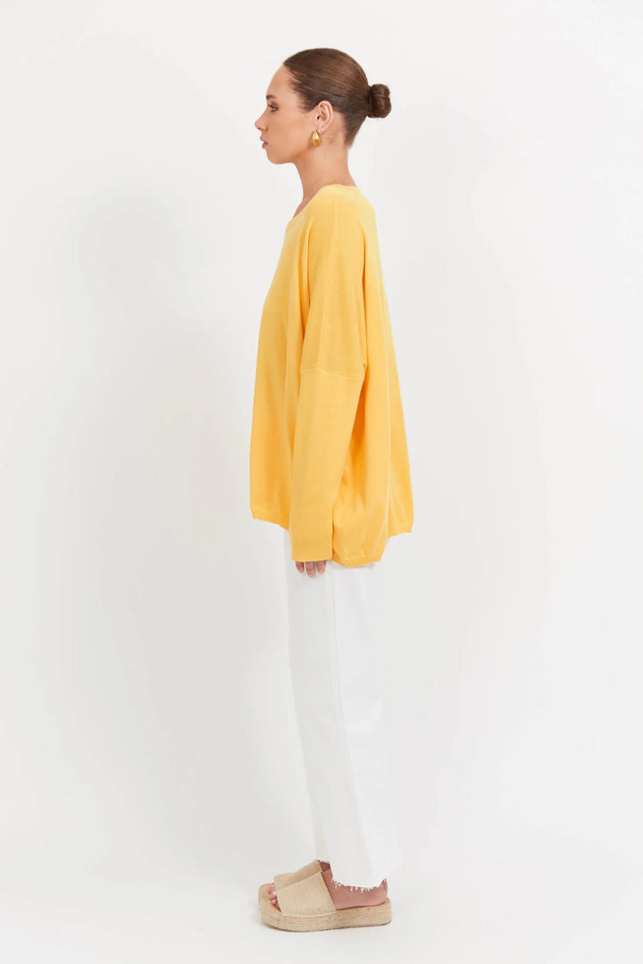 Person wearing a yellow haven top and white pants on a white background