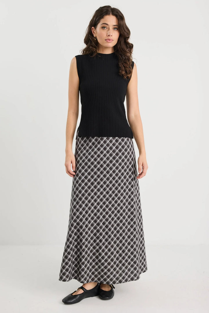 Woman wearing a black sleeveless top and patterned skirt on a white background