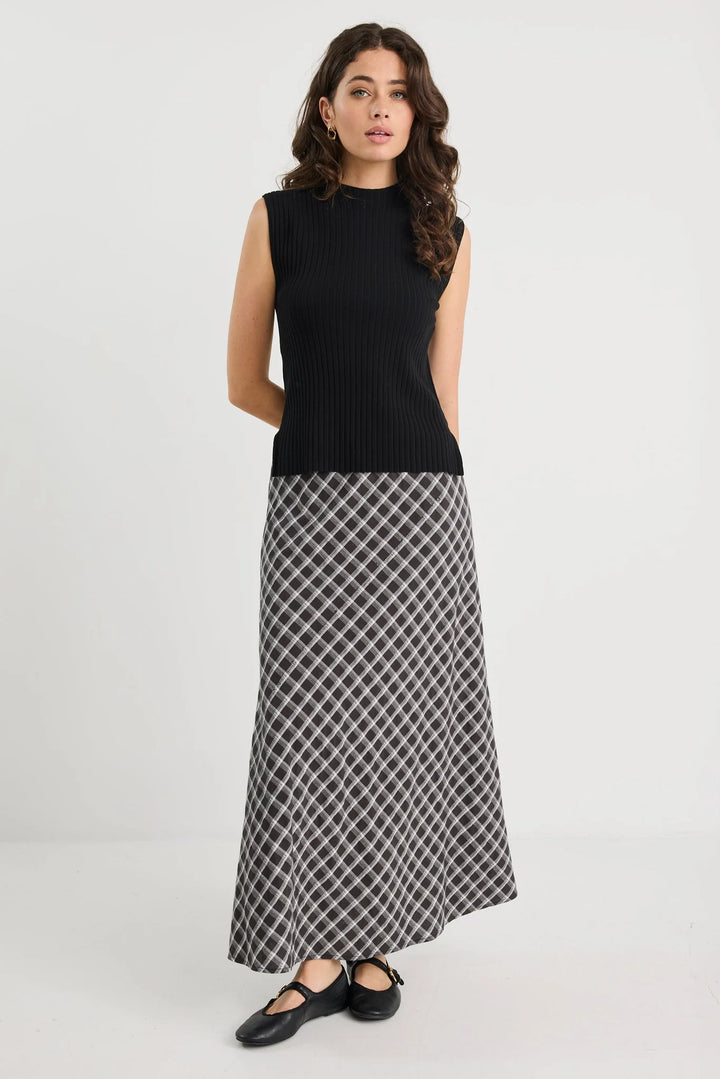 Woman wearing a black sleeveless top and patterned skirt on a white background